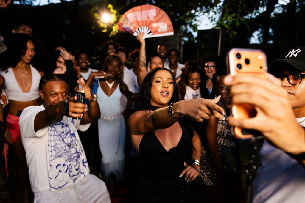 Festa da NegritudeNjoada ao ar livre, à noite: público dançando, cantando e filmando com o celular